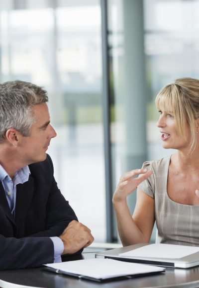 Businessman and woman having discussion at table in office.